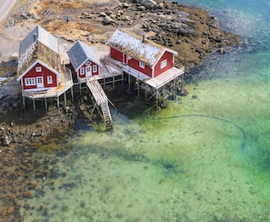 A coastal house with a wooden deck and a staircase leading to a pier. - Aronbua - Valen Cabins (Moskenes)