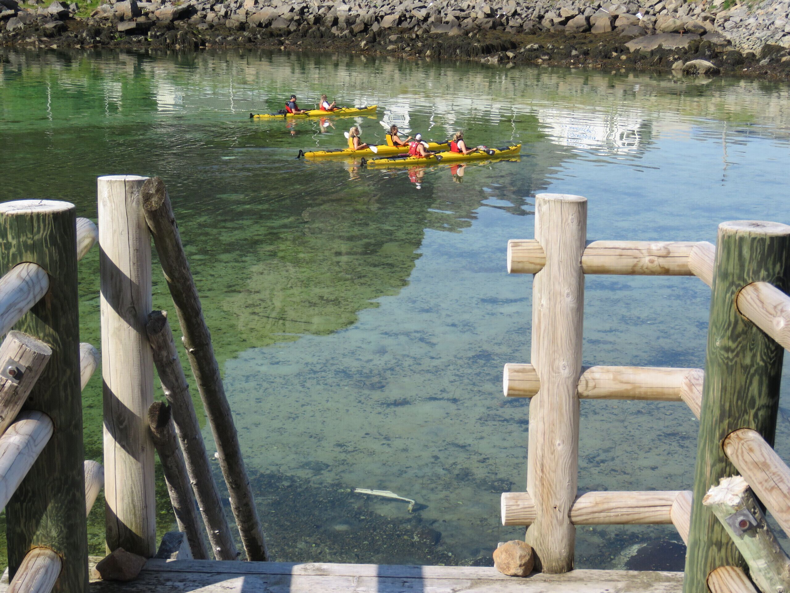 Un muelle de madera con kayaks en el agua.
