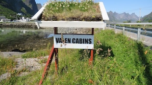 Placa para 'Varen Cabins' com vista para um lago e montanhas ao fundo.