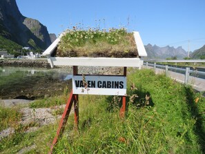 Señal de 'Varen Cabins' con vista a un lago y montañas al fondo.