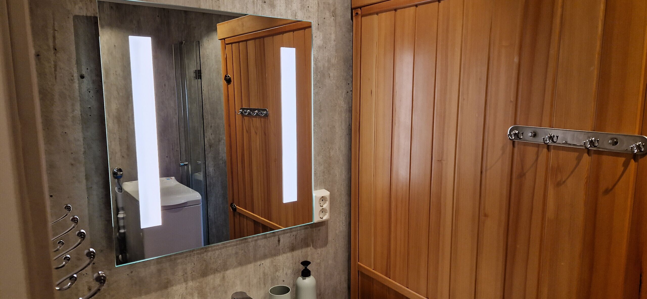 A bathroom with a wooden door, a mirror, and a towel rack.