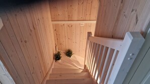 Un escalier en bois avec une rampe blanche et deux plantes en pot à sa base.