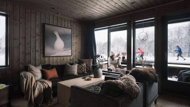 Interno accogliente di una baita con soffitto in legno, un'ampia finestra con vista innevata, un quadro appeso e un'area salotto confortevole.