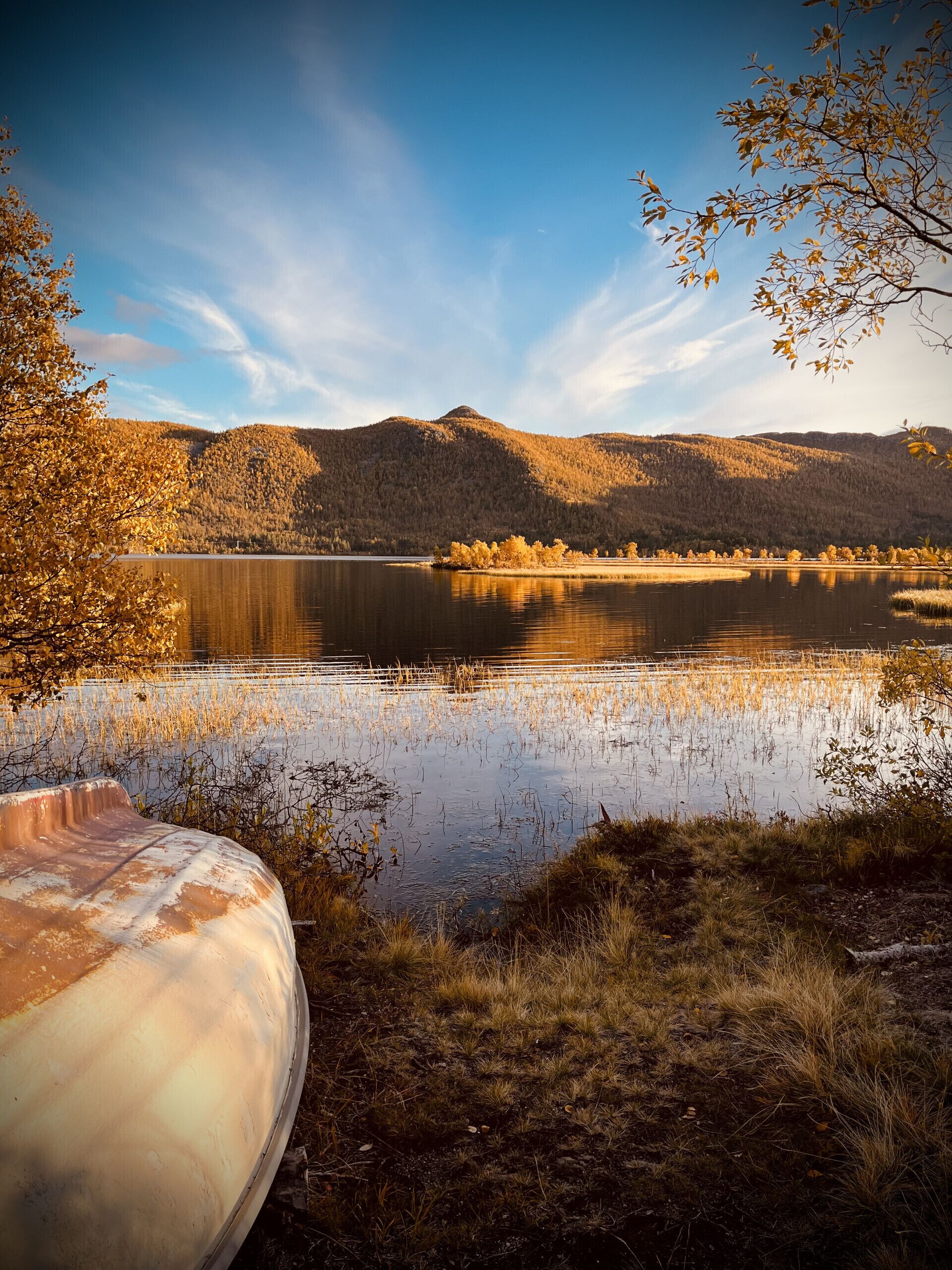 Un lago con un bote, rodeado de colinas y árboles.