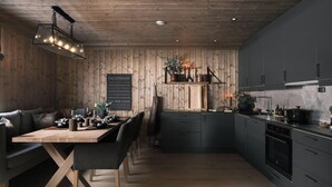 Una cucina moderna con mobili scuri, un tavolo da pranzo in legno e un'accogliente area salotto.