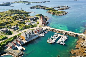 Vue aérienne d’une zone côtière avec un port de plaisance, des bateaux et des bâtiments.
