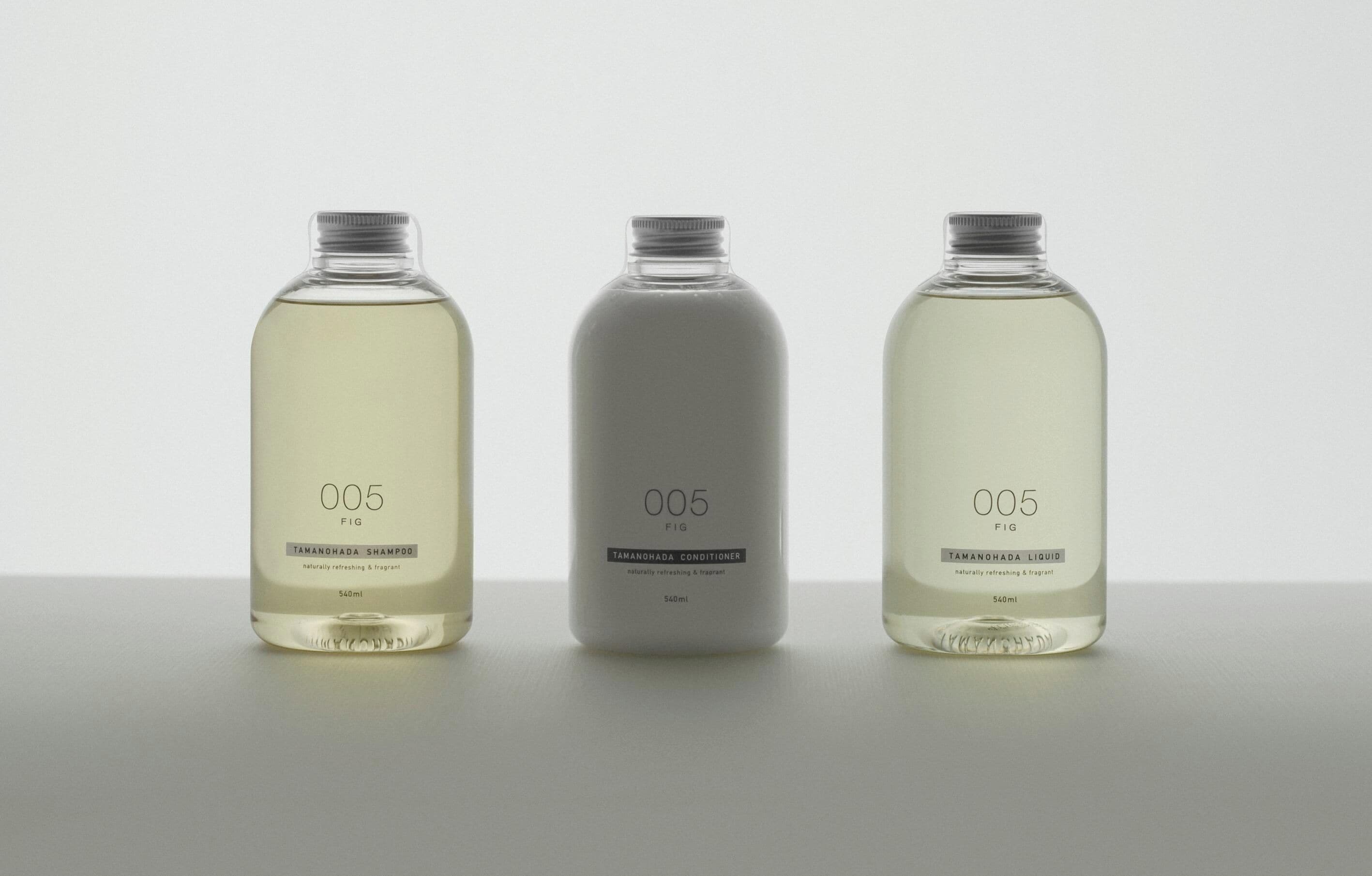 Tres botellas de un producto con la etiqueta '005 FIG' que contienen diferentes tipos de líquido.