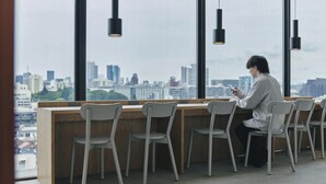 A modern office space with a long wooden desk, multiple chairs, and large windows offering a city view. - 9h nine hours Shinjuku-North (Tokyo)