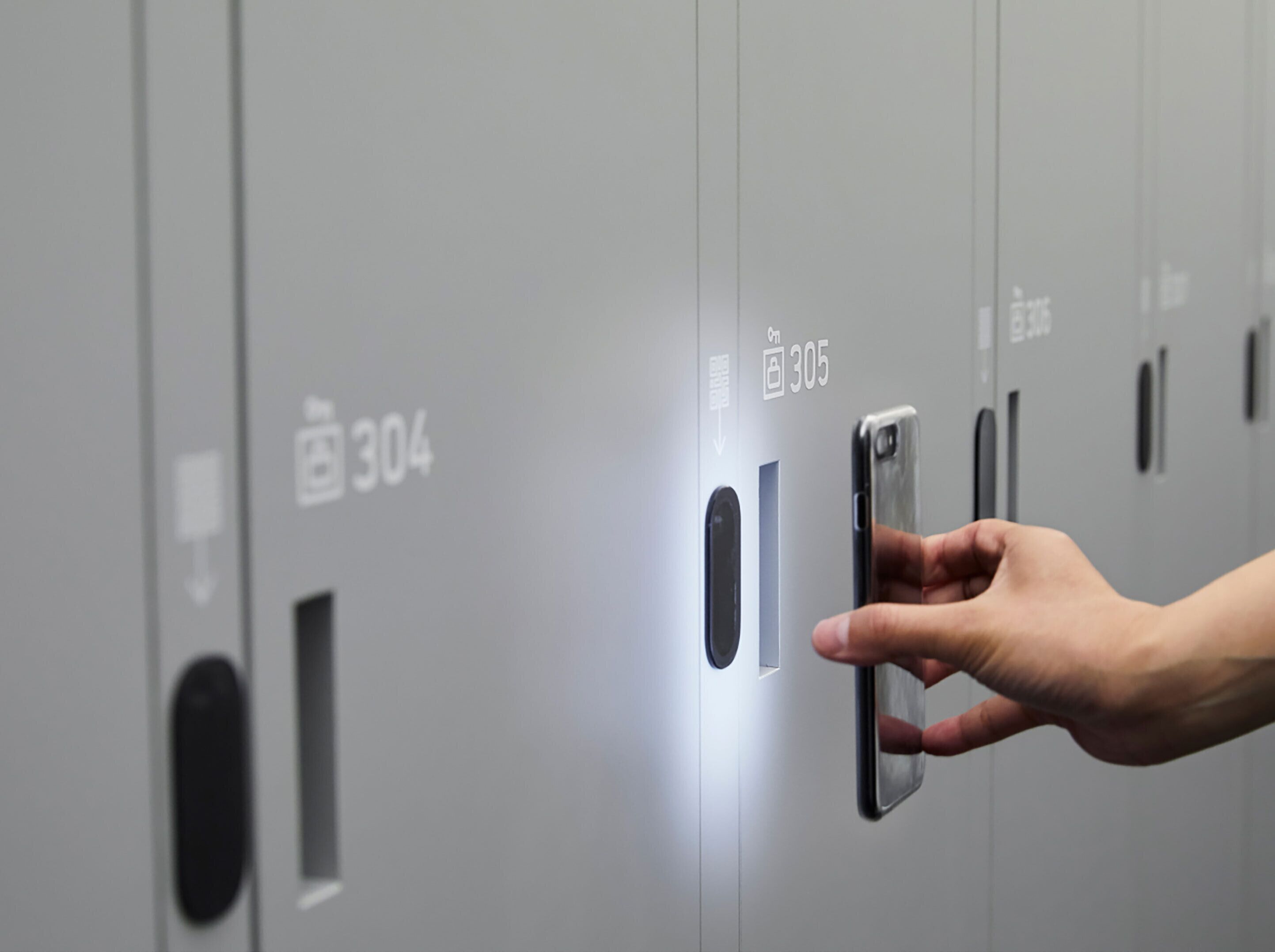 A hand interacting with a digital lock on a grey locker door, with numbers 304 and 305 visible.