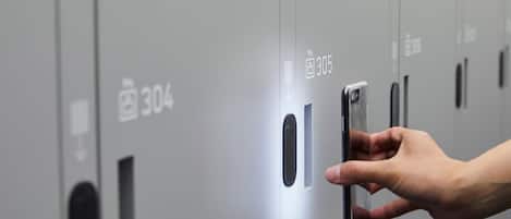 Una mano interactuando con una cerradura digital en la puerta de un locker gris, con los números 304 y 305 a la vista.