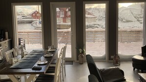 Een eethoek met een tafel voor vier personen, grote ramen en uitzicht op een besneeerd landschap.