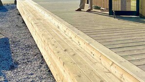 A wooden building with a deck overlooking a beach.