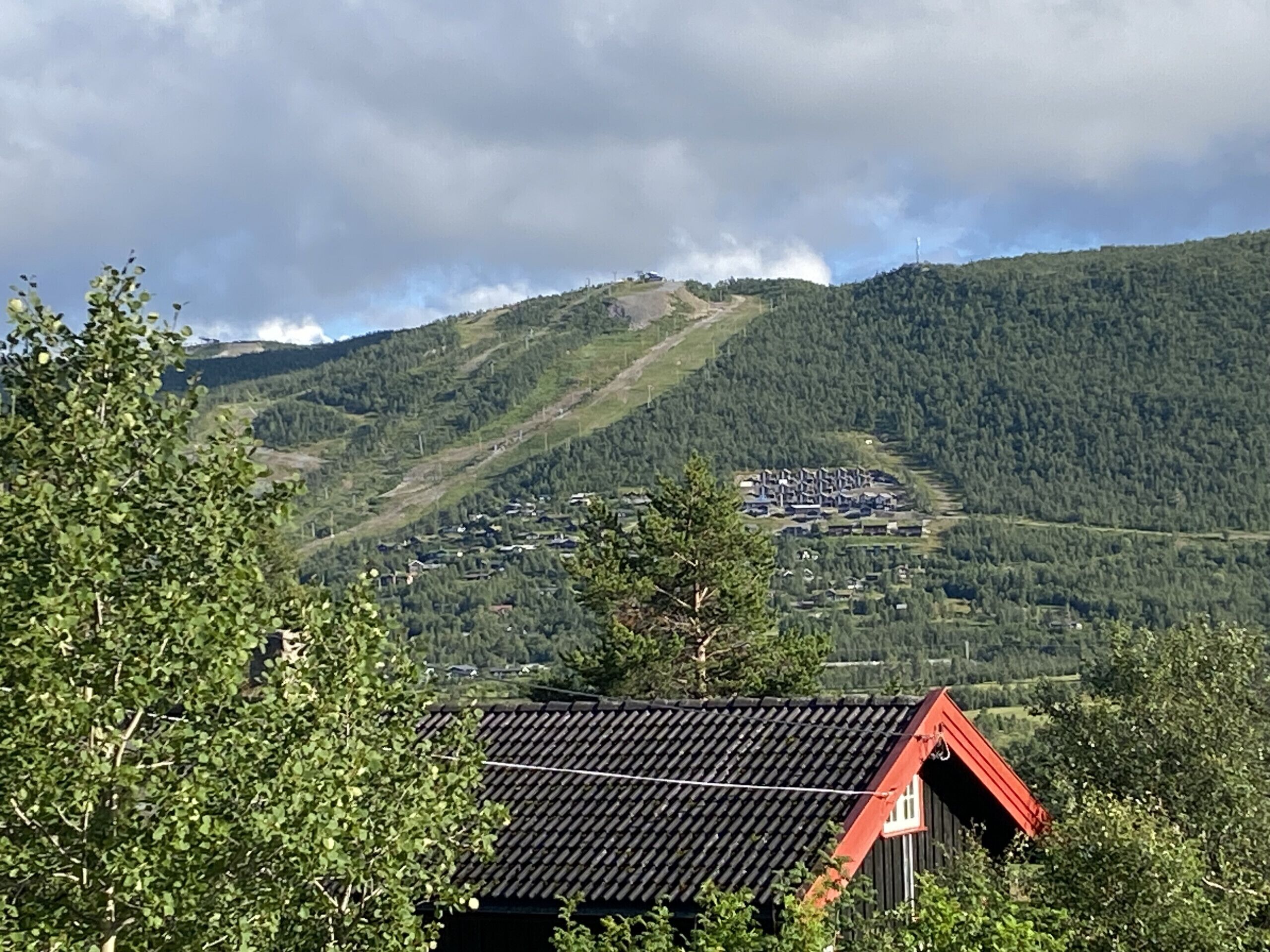 A mountainous landscape with a village and a red-roofed building in the foreground.