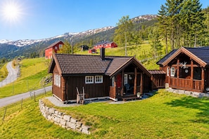 Eine Holzhütte mit Veranda, einer Steinmauer und Blick auf ein Gebirge.