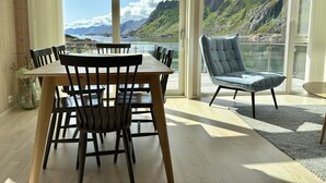 A dining area with a table and chairs, a lamp, and a view of mountains and water.