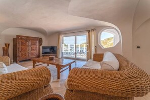 A spacious living room with wicker furniture, a wooden coffee table, and a television. - Elite Collection Royal House (Jacuzzi + Terrace) (Poltu Quatu)