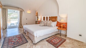 Camera da letto con un letto grande, due tappeti, un comodino e vista sull'esterno.