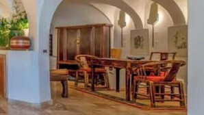 Un interno con soffitti a volta, pavimento in legno e un'area salotto con sedie e tavoli.