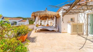 Un cortile con un gazebo in paglia, piante in vaso e pavimento piastrellato.