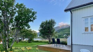 Une maison avec une terrasse, deux chaises et une chaise blanche à l’extérieur.