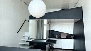 Una sala de estar moderna con un sofá y una cocina con un taburete de bar.