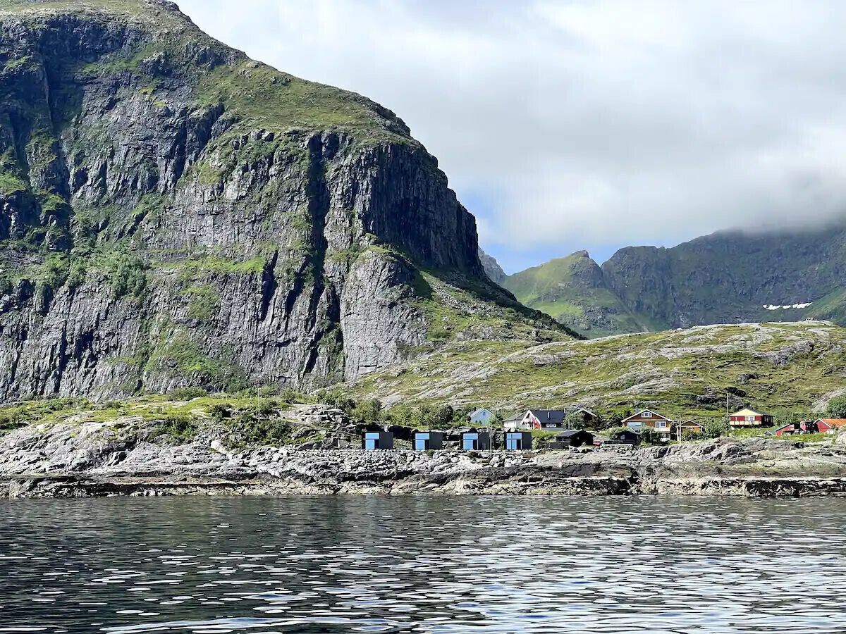 A coastal village with houses along the shore, a rocky cliff, and a body of water.