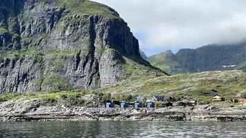 A coastal village with houses along the shore, a rocky cliff, and a body of water.