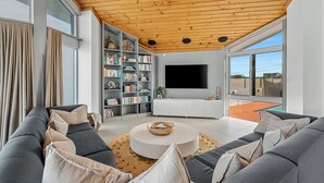 En moderne stue med sofaarrangement, sofabord, bogreol og fladskærms-TV.