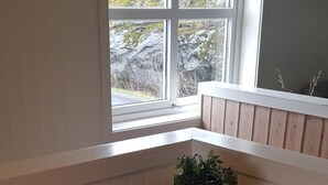 A corner dining table with a potted plant, a red container, and a window with a view of trees.