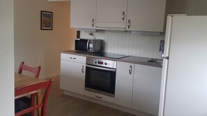 A compact kitchen with a microwave, oven, and refrigerator.
