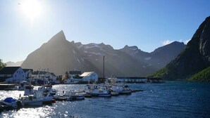 A harbor with boats, buildings, and mountains in the background. - Lofoten panoramic luxury home with sauna (Moskenes)