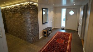 A hallway with a stone wall, a bench, a rug, and a door. - Lofoten panoramic luxury home with sauna (Moskenes)