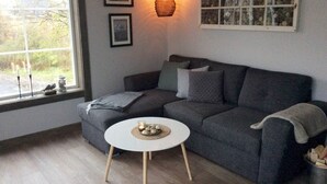 A living room with a grey sofa, a round white coffee table, and a hanging light fixture.