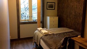 A bedroom with a bed, a window, a dresser, and a framed picture on the wall.