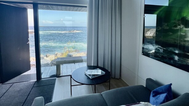 Un saló modern amb un sofà, una taula petita i vista a l'oceà.