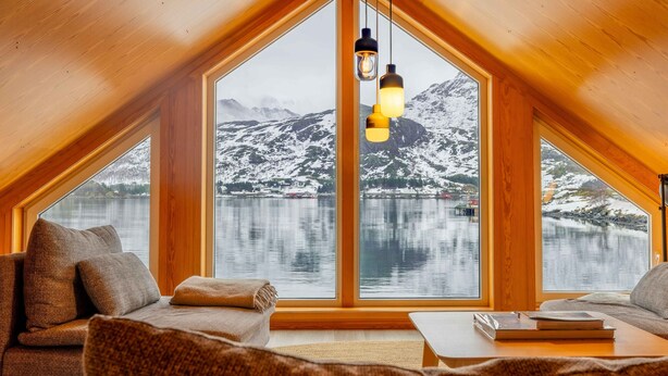 Una habitación acogedora con un gran ventanal, techo de madera y vistas a montañas nevadas.