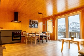 Un interior de madera con cocina, comedor y ventanas amplias.