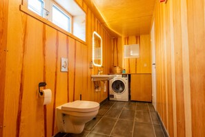 Un bagno compatto con pareti in legno, un water, una lavatrice e un lavandino.