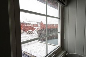 Una ventana con vistas a un paisaje nevado, que incluye un puente y edificios.