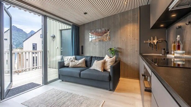 Un interior modern amb un sofà, una zona de cuina i una vista de muntanyes.