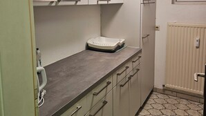 Une cuisine équipée de placards, d’un plan de travail, d’une fenêtre et d’un radiateur.