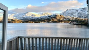 A view from a window overlooking a lake with snow-covered mountains in the background.