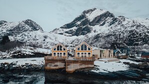 A wooden structure with a reflective water surface, surrounded by snow-covered mountains.