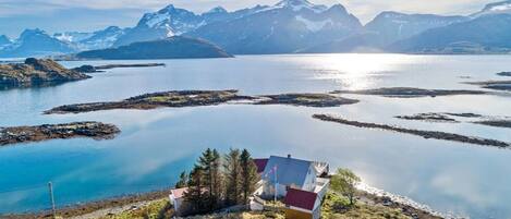 A lakeside property with a small building, clear views of mountains, and a calm lake.