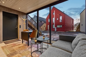 Un intérieur moderne avec un canapé, une table à manger et des chaises, et une vue sur un bâtiment rouge à l’extérieur.