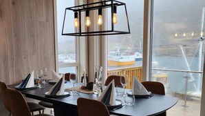 Un espace repas comprenant une grande table, des chaises et un luminaire suspendu.