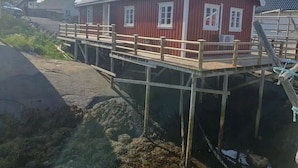 A red building with a wooden deck and a staircase leading to a dock.