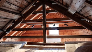 An attic room with wooden beams, a sloped ceiling, and a window.