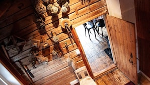 A rustic wooden interior with a loft bed, hanging decorations, and a dining area.