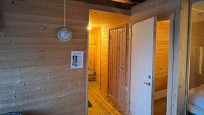 A wooden interior with a wooden floor, a door, and a wall-mounted light fixture. - Tradisjonell Rorbu i fiskeværet Ballstad (Vestvågøy)